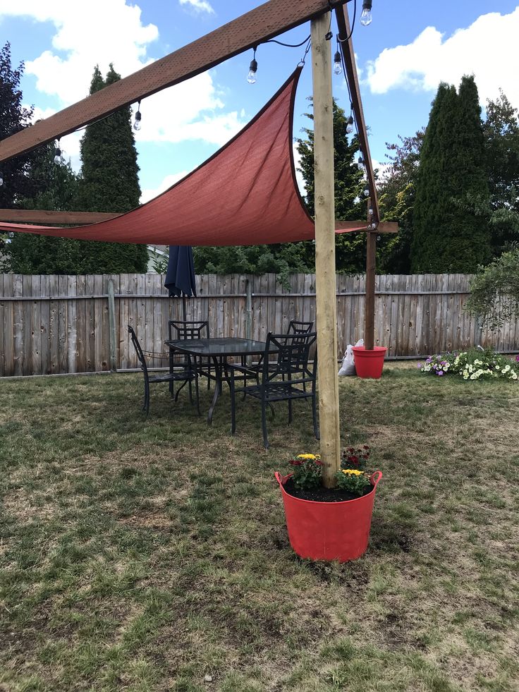 a backyard with a table and chairs under a red awning over the dining area