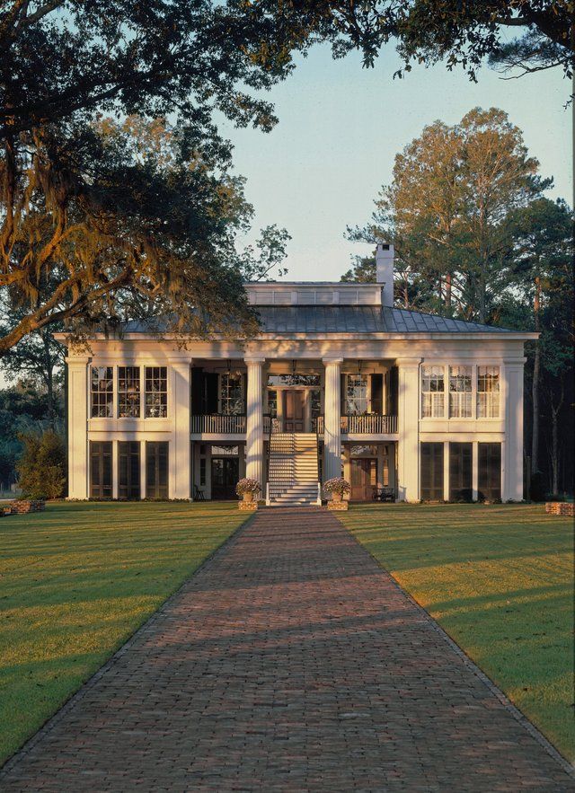 a large white house sitting on top of a lush green field