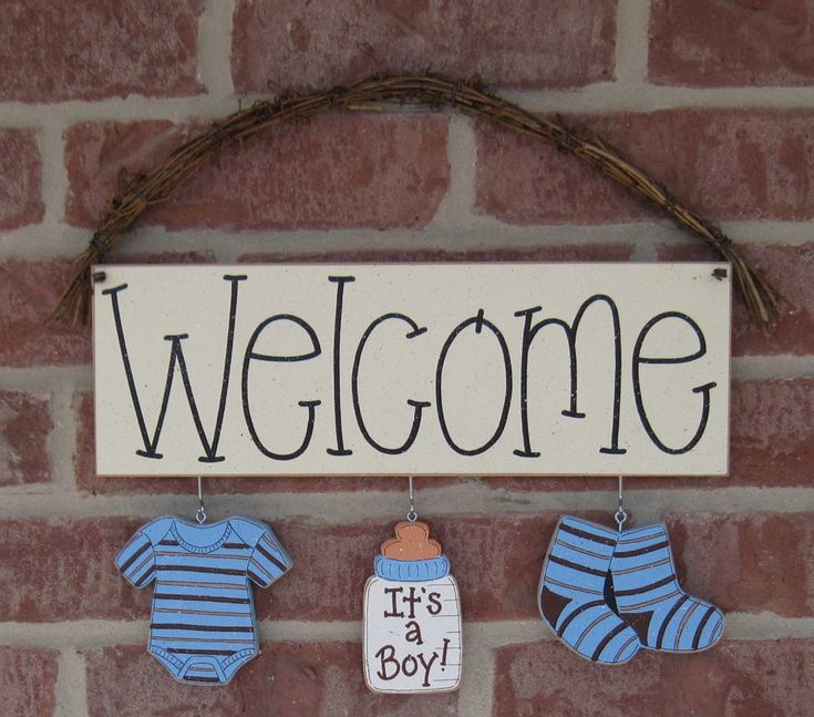 a welcome sign hanging on a brick wall next to baby's booties and socks