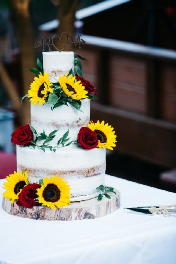 a wedding cake with sunflowers and roses on it