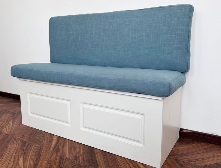 a blue and white bench sitting on top of a hard wood floor next to a wall