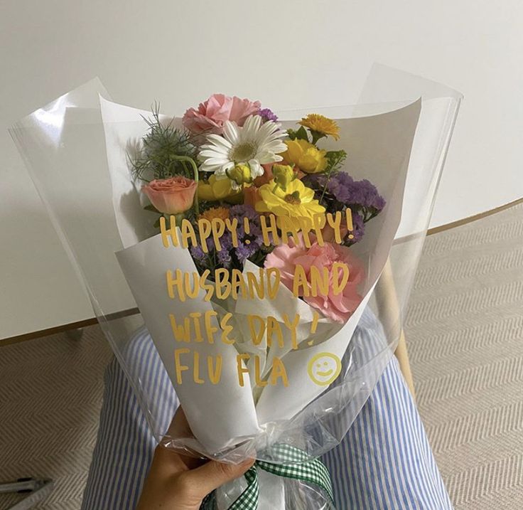 a person holding a bouquet of flowers with the words happy birthday written on it