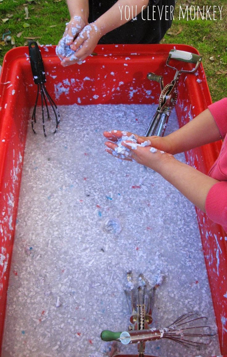 two children are playing in an outdoor sand and water play area that is red with white sprinkles