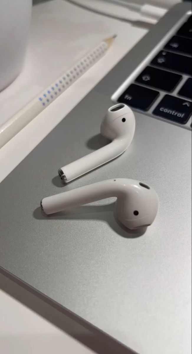 two ear buds sitting on top of a laptop computer