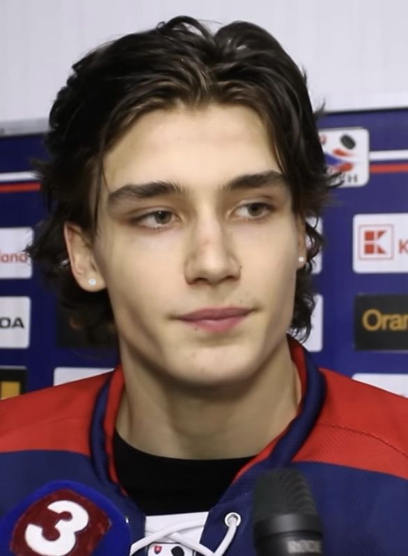 a young man in a red and blue jersey is holding a microphone to his ear