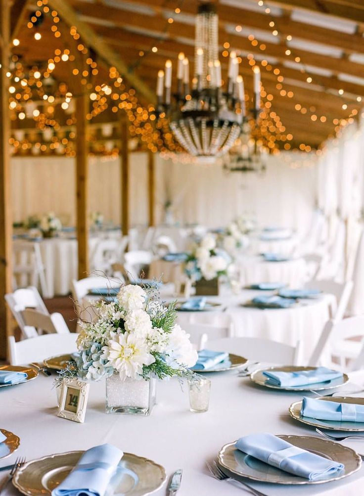 the tables are set with white and blue linens for an elegant wedding reception at the barn