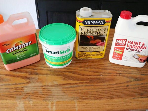 several different types of furniture cleaners on a wooden table with one gallon of paint