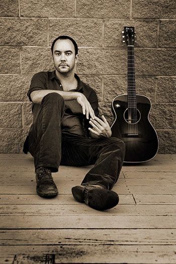 a man sitting on the ground next to a guitar