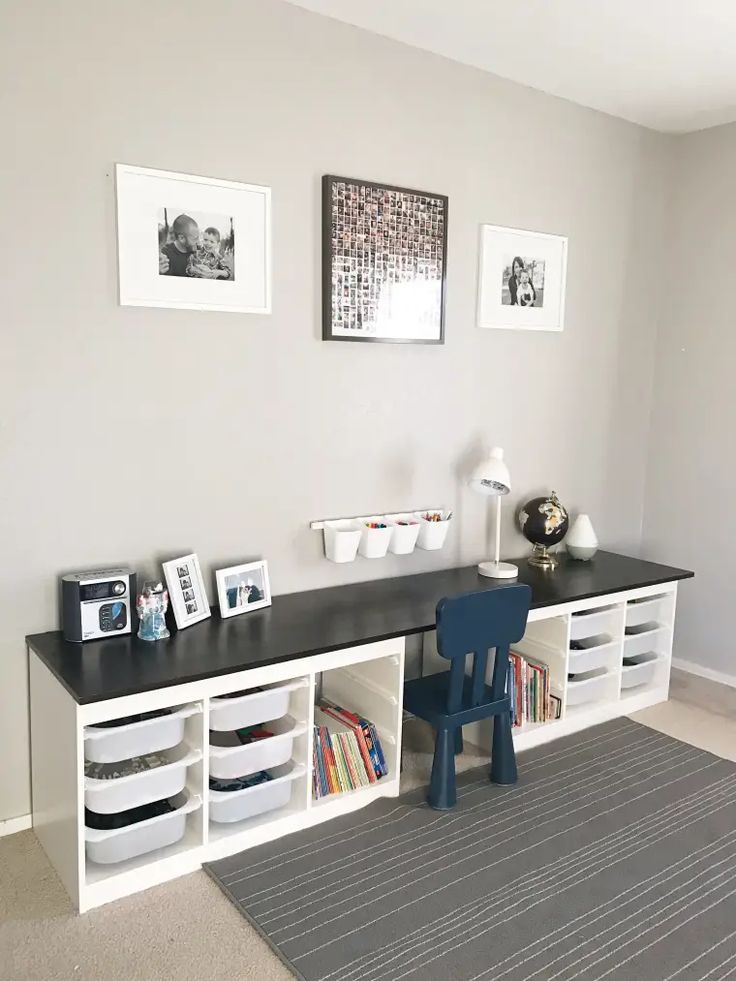 there is a desk with several bins on it and two pictures above the desk