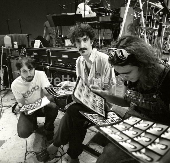 three young men sitting next to each other in front of microphones and keyboards on stage