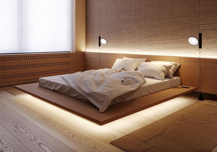 a large bed sitting on top of a wooden floor next to a white rug and window