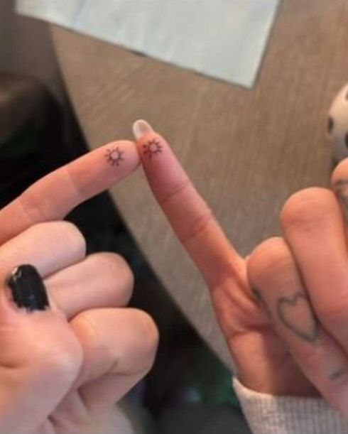 two people with tattoos on their fingers making the peace sign and heart shaped fingernails