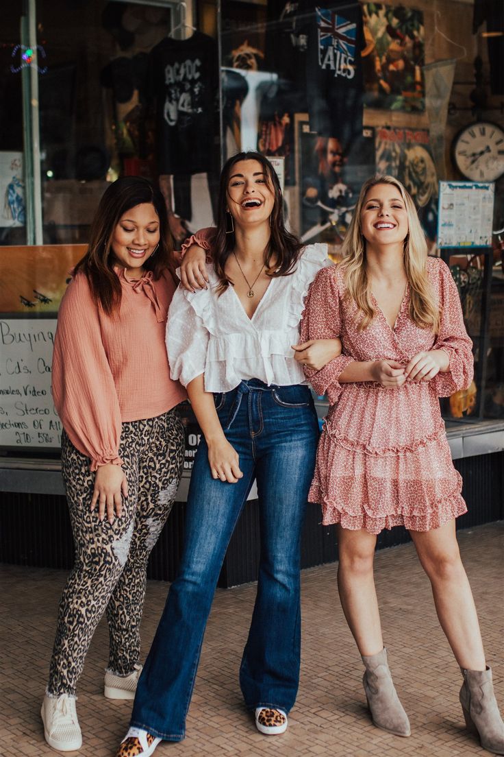 three women standing next to each other in front of a store smiling at the camera