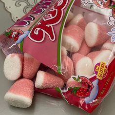 pink and white marshmallows sitting in a bag on a counter top next to a packet of strawberry shorties