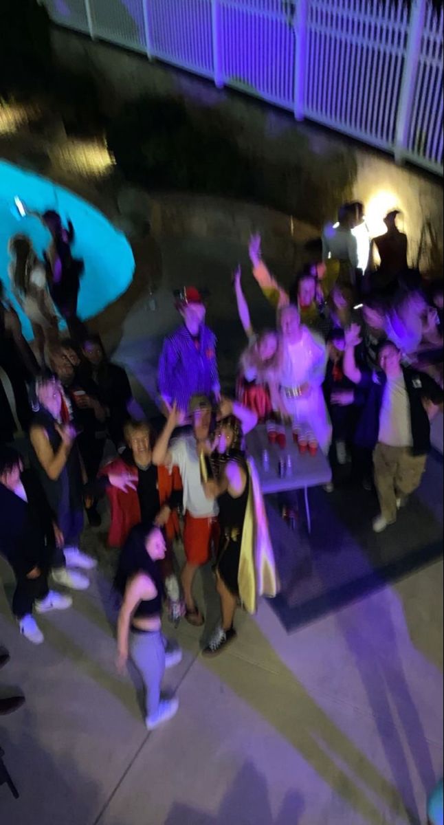 a group of people standing around each other in front of a building at night time