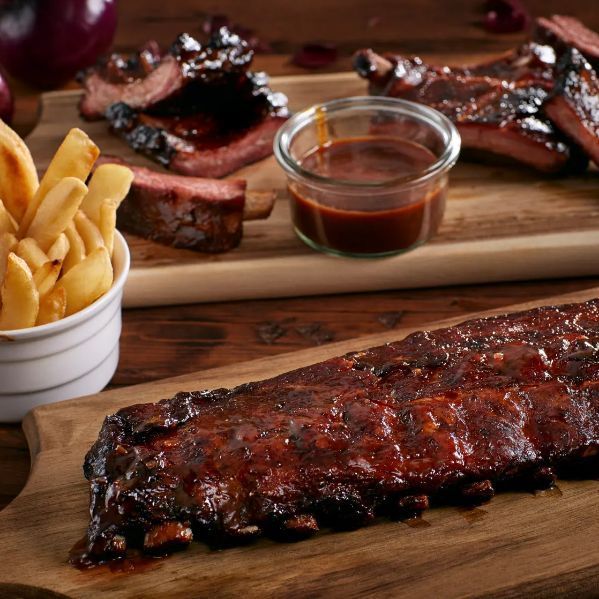 ribs, fries and sauces sit on wooden cutting boards