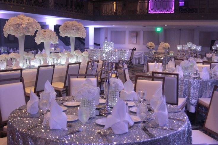 the tables are set up with white flowers and centerpieces for an elegant event