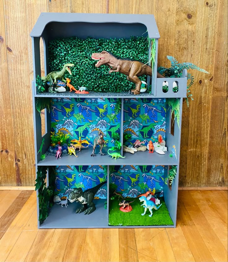 a toy dinosaur bookcase with dinosaurs and other toys in it on a wooden floor