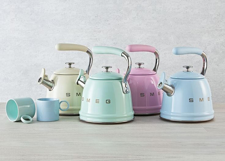 four different colored kettles sitting on top of a wooden table next to each other