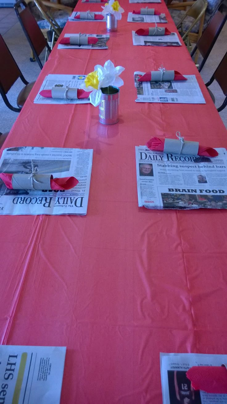 the long table is covered with newspapers and flowers