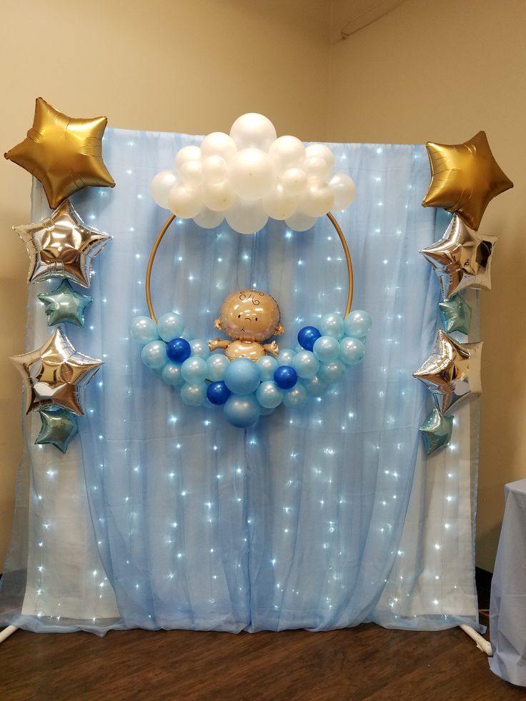 a backdrop with balloons, stars and a baby's crib in the center