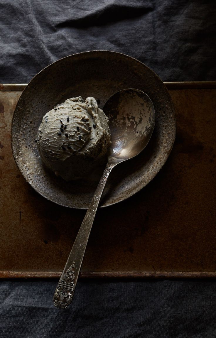 a spoon sitting on top of a metal plate next to a scoop of ice cream