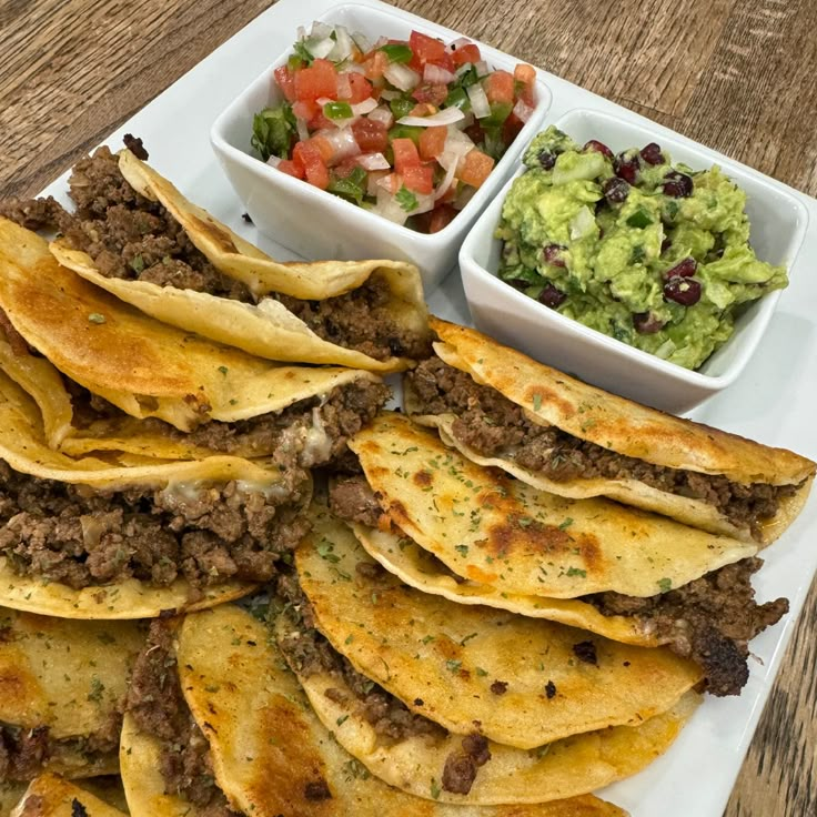 tortillas and guacamole are served on a white platter with salsa