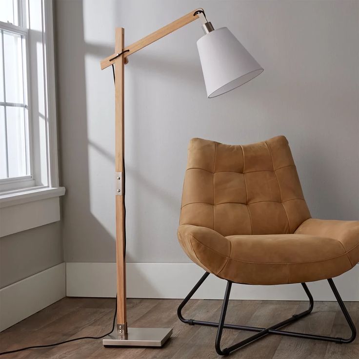 a brown chair sitting in front of a lamp on top of a wooden floor next to a window