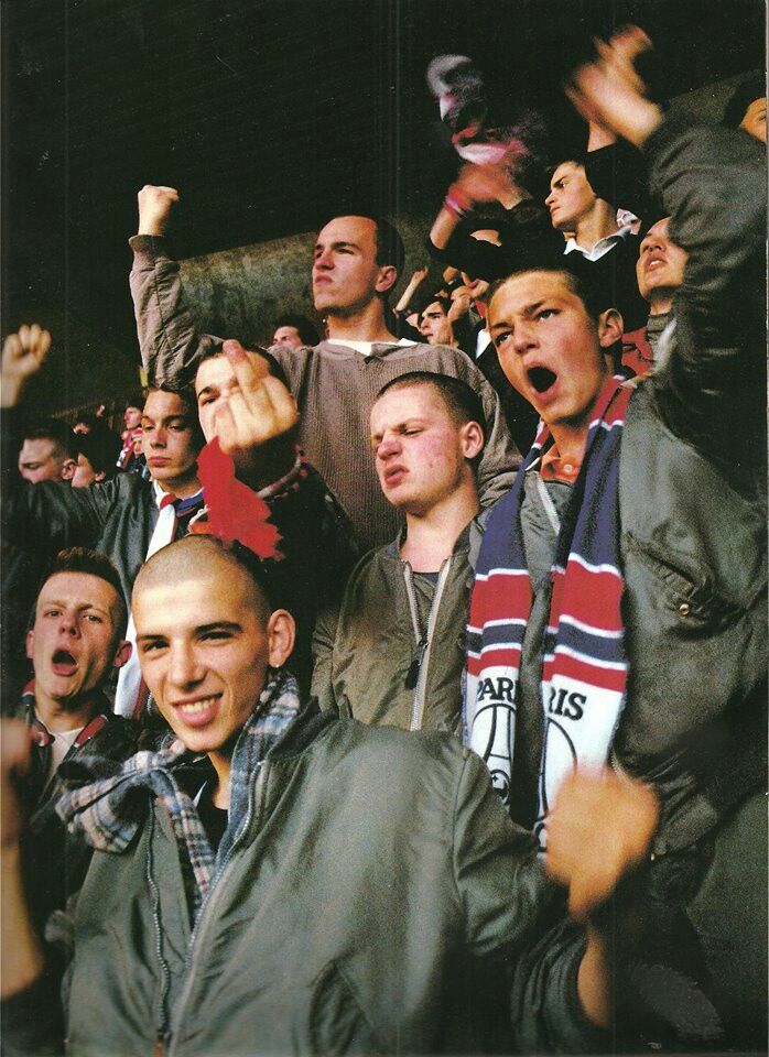 a group of men standing next to each other in front of a crowd with their hands up