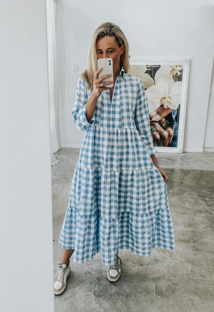 a woman taking a selfie while wearing a blue and white checkered shirt dress