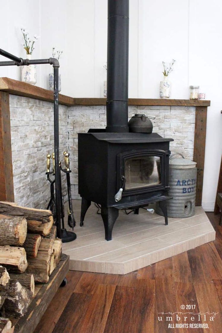 a wood burning stove sitting on top of a wooden floor next to a pile of logs