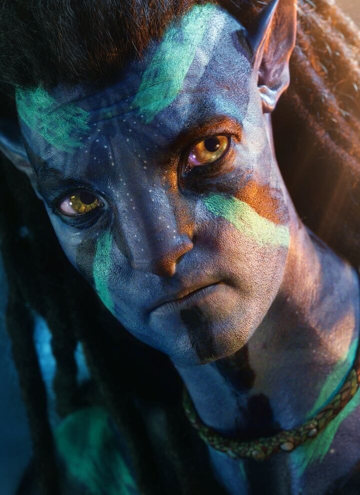 a man with blue and green paint on his face is looking at the camera while wearing dreadlocks