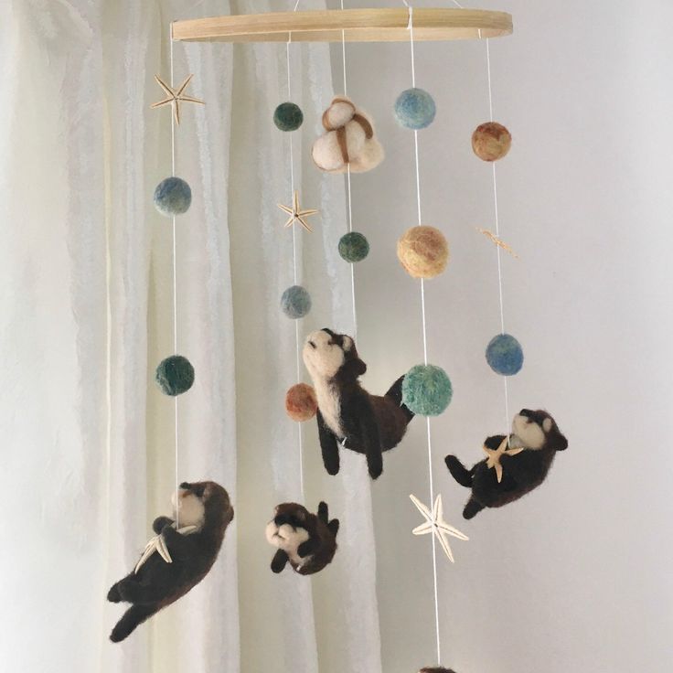 an animal mobile hanging from a curtain with balls, stars and other objects attached to it