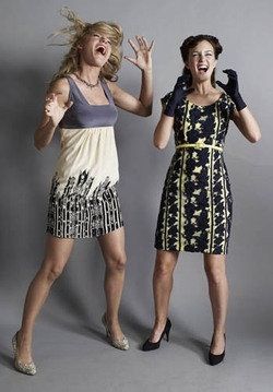 two women in dresses are laughing and posing for the camera with their hands up to their mouths