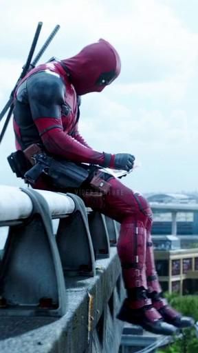 a man dressed as deadpool sitting on a ledge