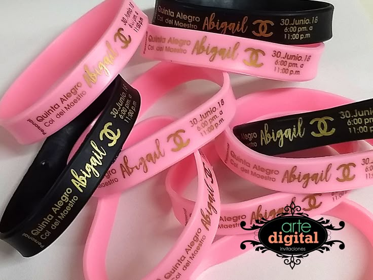 pink bracelets with black and gold lettering on them are sitting next to each other