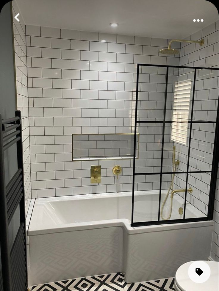 a white bathroom with black and white tile on the floor, shower, toilet and bathtub