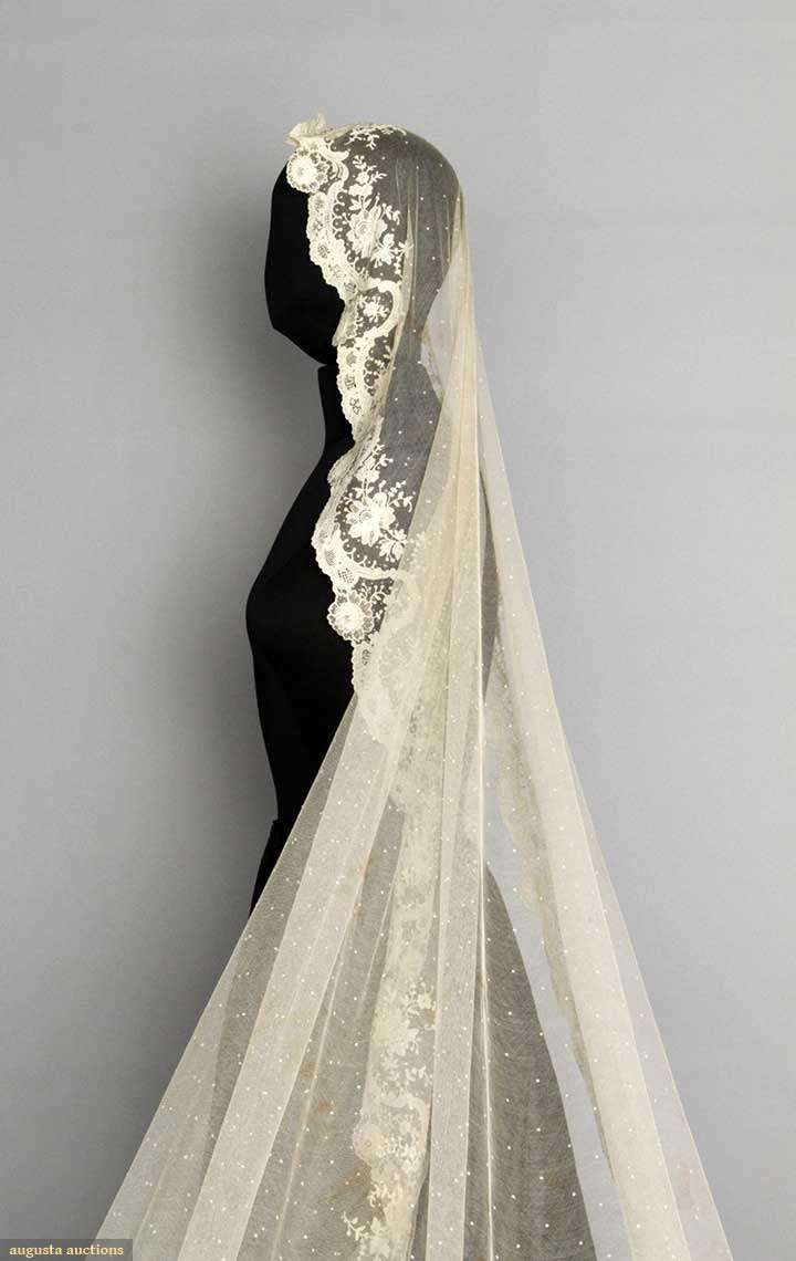 a wedding veil with white lace on the top and bottom, sitting on a mannequin's head