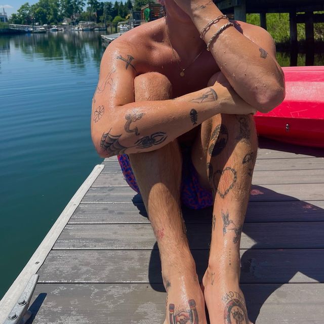 a man with tattoos sitting on a dock