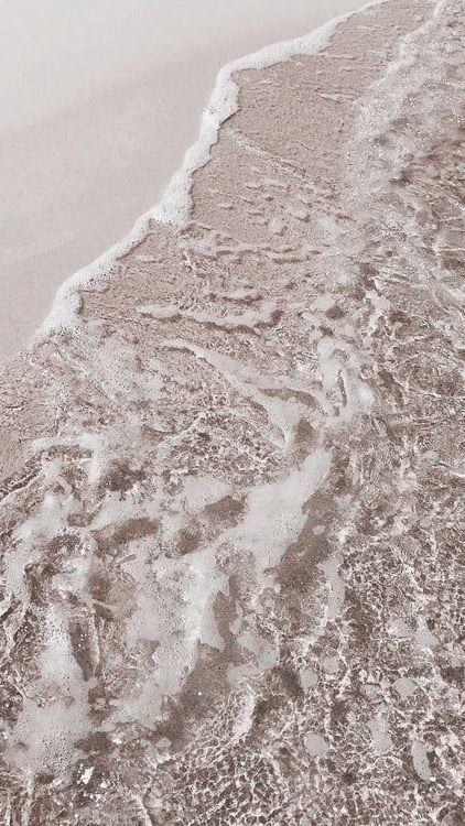 an image of the beach with waves coming in from the water and sand on the shore