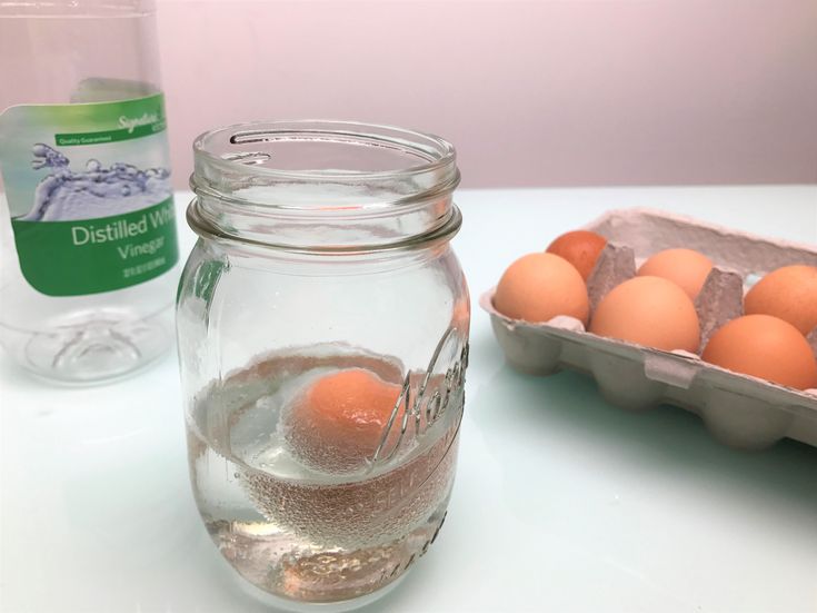 eggs are in a glass jar next to a carton of water and an egg tray