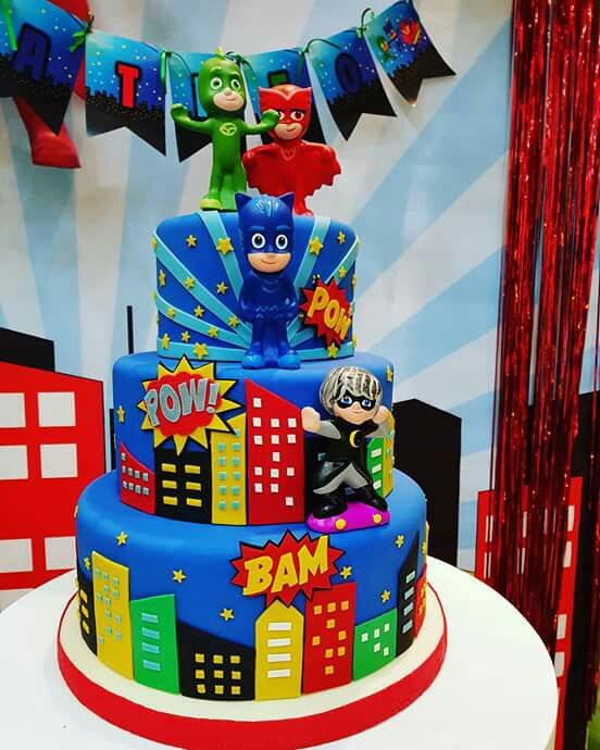 the birthday cake is decorated with superheros and batman characters on it's sides