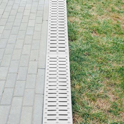 a metal grate sitting on top of a green grass covered field next to a sidewalk