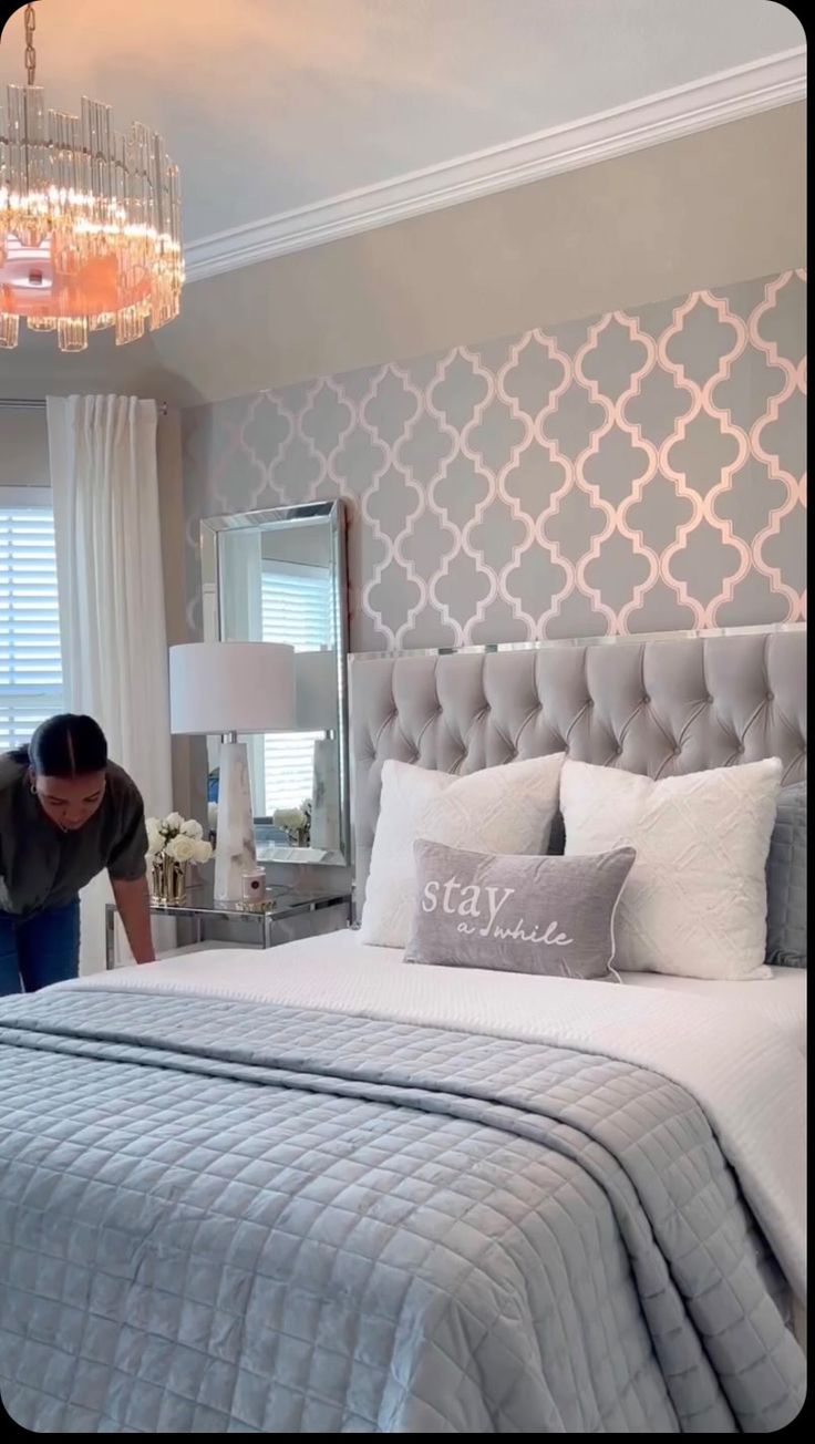 a woman is placing pillows on a bed