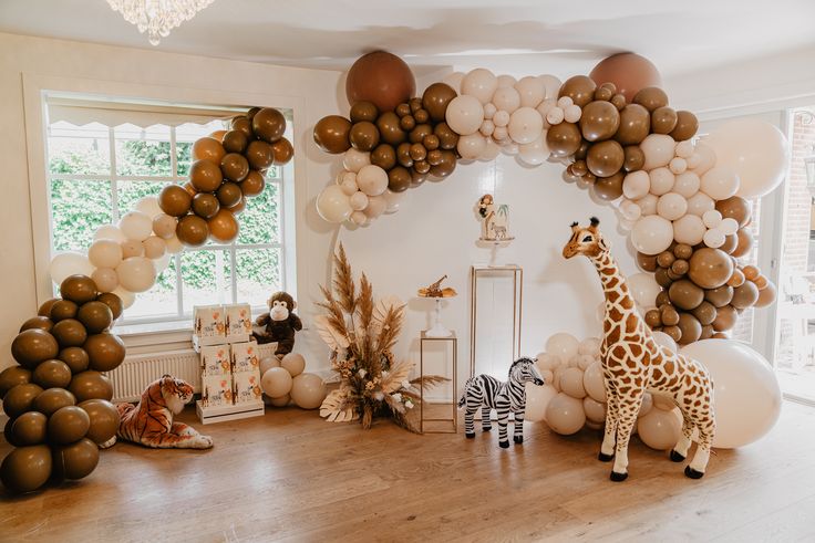 a room filled with balloons and giraffes next to a zebra on the floor