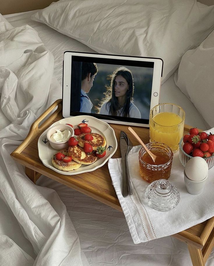 an ipad and breakfast tray on a bed