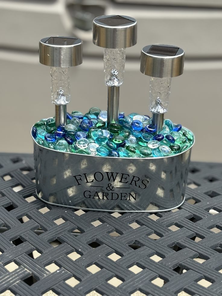 three metal candlesticks in a tin with blue and green glass beads on them