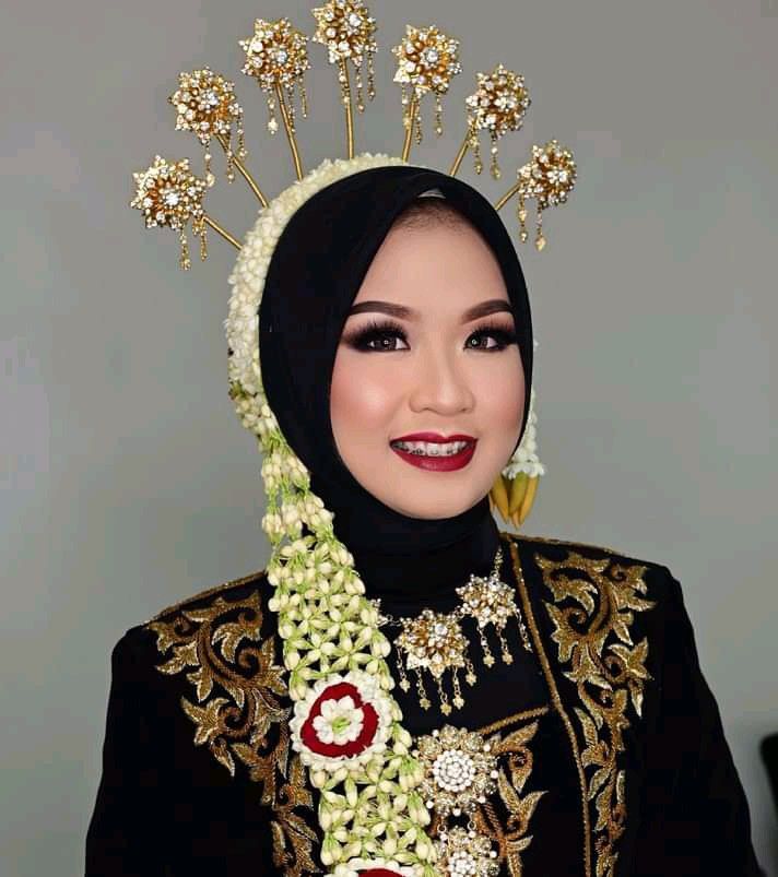 a woman wearing a head piece with flowers and pearls on it's head is smiling at the camera