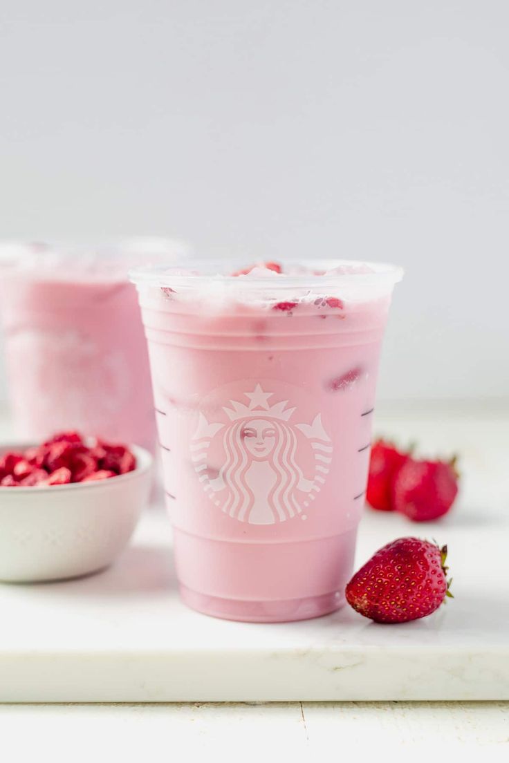 two cups filled with ice cream and strawberries on top of a white countertop