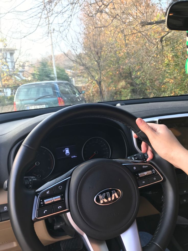 a person driving a car with their hand on the steering wheel